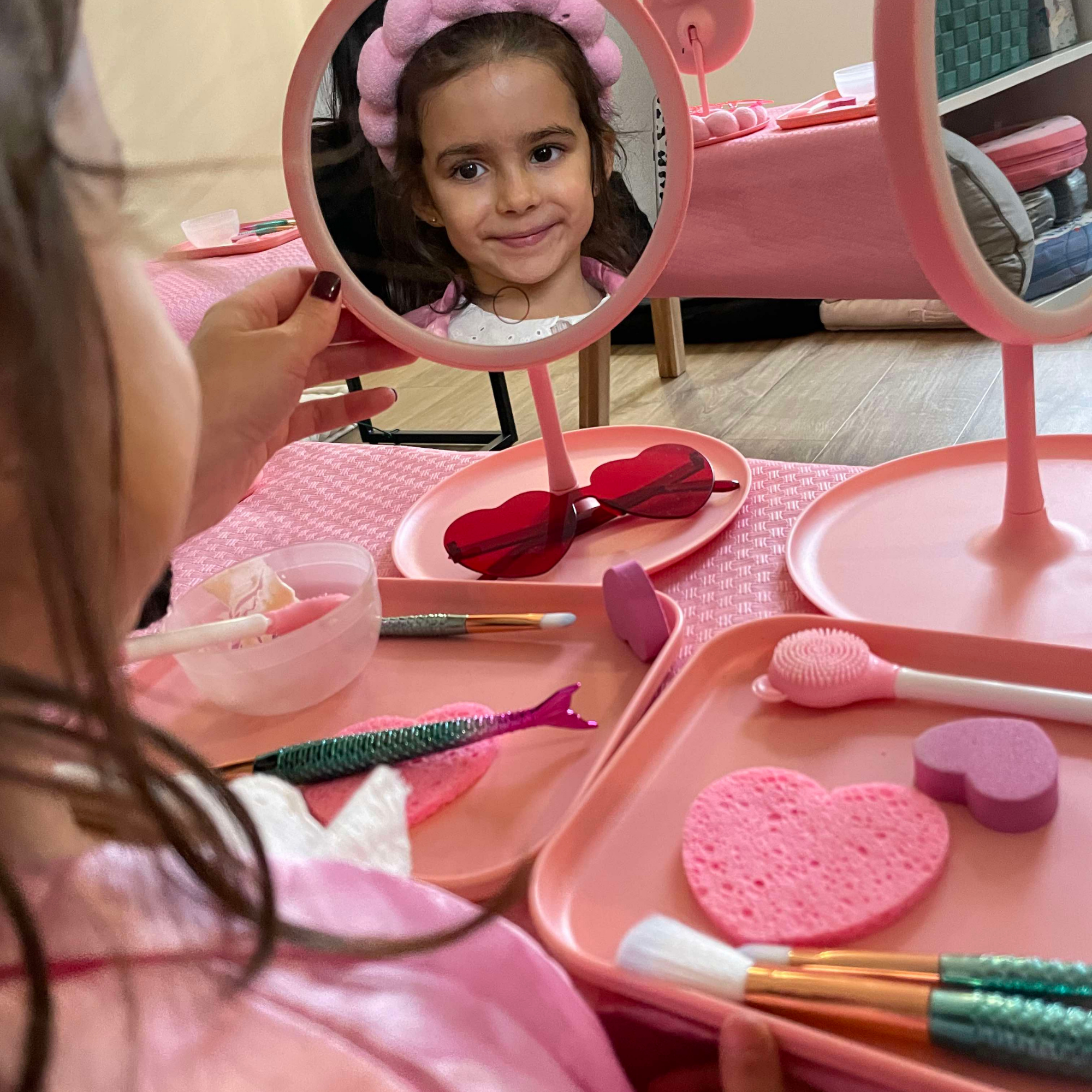 Petite fille souriante devant le miroir pendant son soin visage